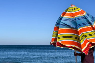 A man holding an open parasol on the beach
