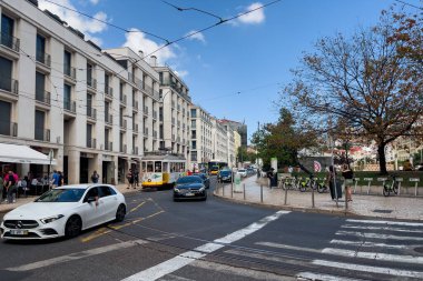 Lizbon 'da eski bir tramvayın yanından geçen arabalar