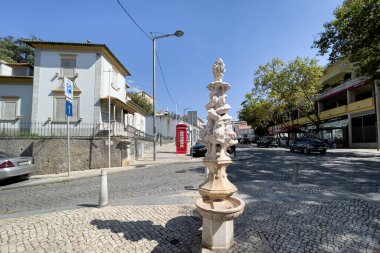 Sintra 'da kaldırımda arkasında kırmızı telefon kulübesi olan bir çeşme.