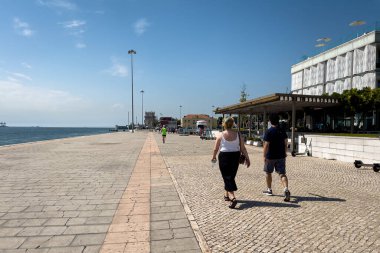 Lizbon 'da Bom Sucesso yakınlarındaki Tagus nehrinin kıyısında yürüyen insanlar.