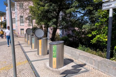 Sokak boyunca paslanmaz çelik çöp bidonları.