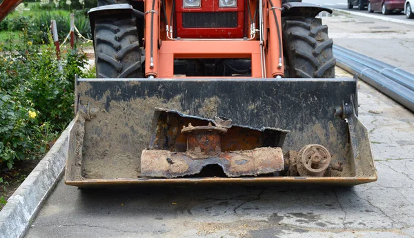 old rusty and corroded pipe holding in a tractor bucket. repair to replace iron pipes with plastic ones. sewerage or water supply during repair