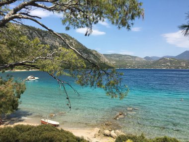 Mavi dağları ve turkuaz suyu olan deniz manzarası.