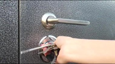 Kadın bir evin kapısını bir sürü anahtarla açıyor. 4K video görüntüleri.