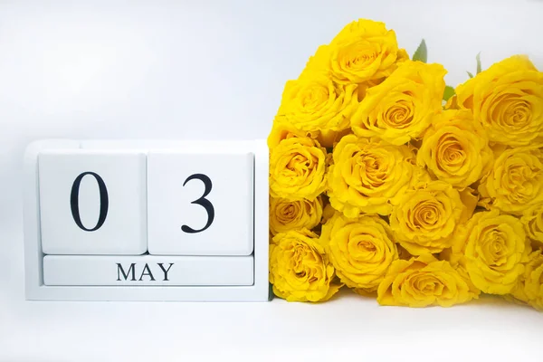 3 de mayo en un calendario blanco, de madera y un ramo amarillo de rosas se encuentran lado a lado —  Fotos de Stock