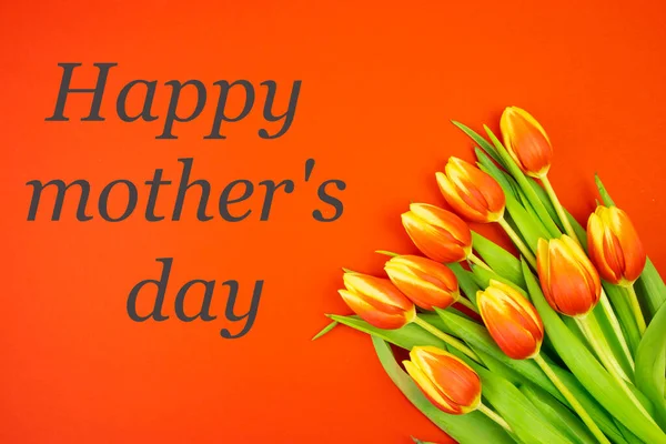 Kırmızı zemin üzerinde sarı-kırmızı laleler ve siyah harflerle Mutlu Anneler Günü yazılıdır. — Stok fotoğraf