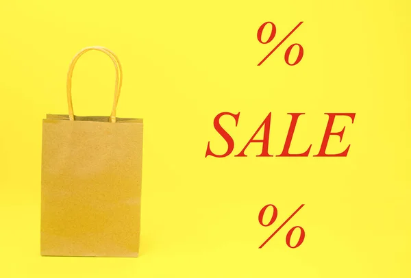 Papírová taška maketa na žlutém pozadí a nápis PRODEJ s procentuálním podílem. — Stock fotografie