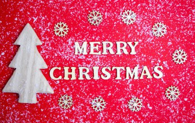 Mutlu Noeller kartı, kırmızı zemin üzerinde ahşap harfler, kar, Noel ağacı, kar taneleri. Tatil kavramı, tebrikler, davetiyeler, promosyonlar, sürprizler. Yüksek kalite fotoğraf