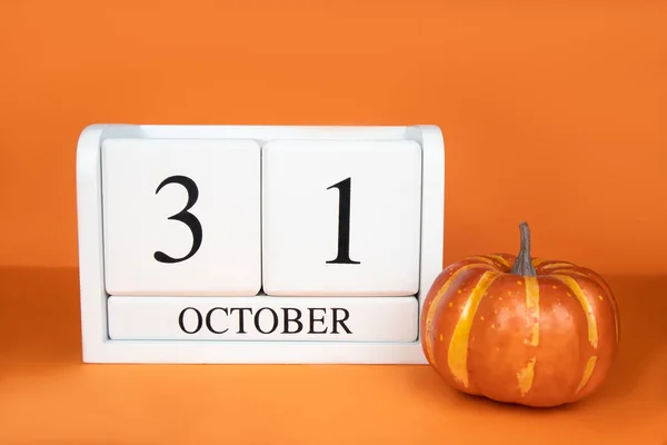 万圣节 十月三十一日是一个白色的木制日历 背景是橙色的 旁边是南瓜 明信片的概念 高质量的照片 图库图片