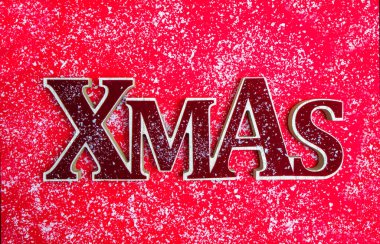 Noel zamanı. Üzerinde kırmızı bir zemin üzerinde kırmızı renkli ahşap harflerle Xmas yazan bir kartpostal. Kartopunun üstünde. Kartpostal, bayram, davetiye, tebrik, duyuru, hediye. 