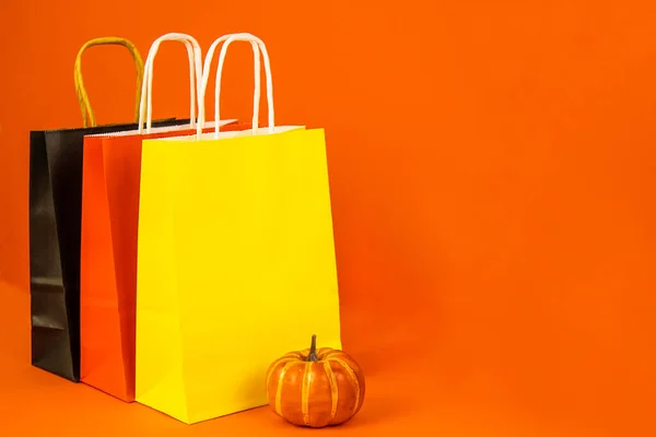 Paper bags yellow, red, black and pumpkin on an orange background. Banner with copy space. The concept of sale, promotion, shopping, shops, gifts, text, holiday, poster, layout,business,purchases