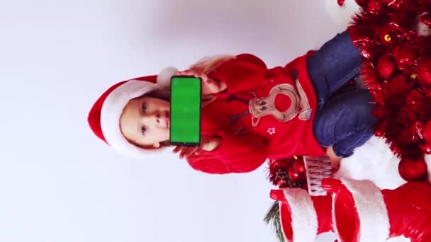 Weihnachten Ein Kleines Mädchen Hält Ein Telefon Mit Grünem Bildschirm — Stockvideo