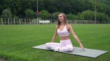 Dışarıda, yeşil çimlerde egzersiz yapan bir kız.