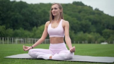 Lotus pozisyonunda oturan ve yoga yapan bir kadın. Esneme egzersizleri ve esneklik
