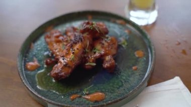 Yavaş çekim, kamera soslu tavuk kanadı tabağının üzerinde dönüyor.