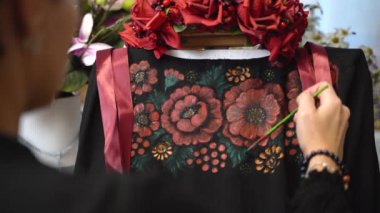 View from behind the shoulder, the girl draws flowers on clothes