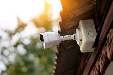 Ev sahibinin evde olmadığı zamanlarda akıllı telefondan izleyebileceği bir evin çatısına IP güvenlik kamerası yerleştirilmiş. Konsept: Ev güvenlik sistemi teknoloji aygıtı.                