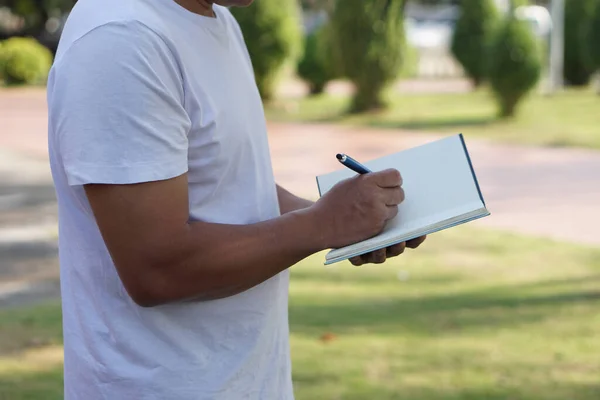 Mężczyzna Pisze Notatniku Outdoor Parku Wieczorem Koncepcja Pisanie Codziennym Życiu — Zdjęcie stockowe