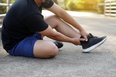 Koşucu, koşudan, koşudan ve egzersizden sonra acı veren ayak bileğini incitir. Konsept: spor yaparken veya spor yaparken bilek burkulması..                                     