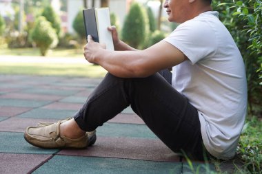 Adam parkta kitap okuyordu. Sıcak bir atmosfer. Konsept: rahatlama zamanı, hobi, hobi. Kendine kitap, dergi, roman okumak için zaman ayır. Günlük hayatta okumak. Eğitim, bilgi, zevk