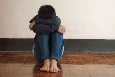 Bunalımlı çocuk yerde tek başına oturur, üzgün hisseder ve ağlar, dizine sarılır. Covid-19 salgınında kendini izole eden ya da evde karantina altına alan bir çocuk. Evimi özledim. Yapayalnız. Korku.
