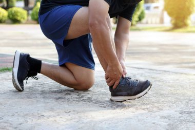 Koşucu, koşudan, koşudan ve egzersizden sonra acı veren ayak bileğini incitir. Konsept: spor yaparken veya spor yaparken bilek burkulması.. 