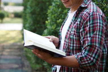 Adam açık hava parkında kitap okuyor. Konsept: rahatlama zamanı, hobi, hobi. Kendine kitap, dergi, roman okumak için zaman ayır. Günlük hayatta okumak. Eğitim, bilgi veya zevk.          