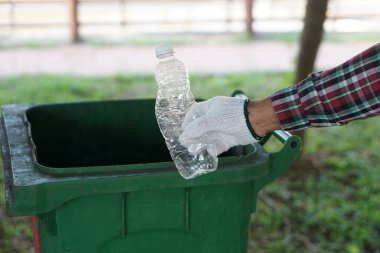Elleri boş plastik şişeyi çöp kutusuna koymak için tutuyor. Geri dönüşüm çöplerini ayırmak. Geri dönüşüm için atık ayırma. Çevre koruma. Sıfır atık.      