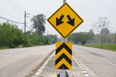 Uyarı sarı. Tayland 'ın kırsal kesiminde iki ok aşağıda trafik işareti var..                               