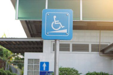 Tekerlekli sandalyede oturan kişinin sembolü olan mavi tabela. Tayland 'daki umumi tuvaletin önünde engelli insanlara hizmet ve kolaylık sağlamak için duruyor..       