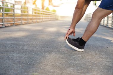 Koşucu bacağına dokunmak için elleri kullanarak bacağını esnetiyor. Konsept: egzersiz yapmadan önce vücut ısısını arttırmak ya da spor yapmak kas sakatlığını azaltmak içindir. Metin ya da sözcük eklemek için boşluk kopyala.