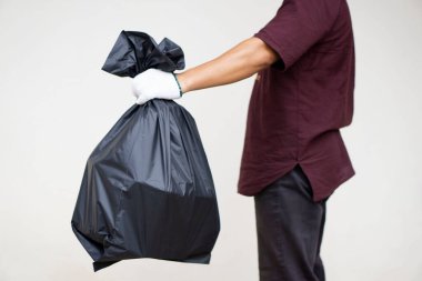 Adamın elinde içinde çöp olan siyah plastik torba var. Atık yönetimi kavramı. Çevre sorunları. Günlük ev işleri. Çöpü at..