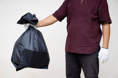 Adamın elinde içinde çöp olan siyah plastik torba var. Atık yönetimi kavramı. Çevre sorunları. Günlük ev işleri. Çöpü at..