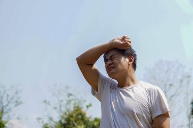 Asyalı orta yaşlı bir adam kendini sıcak hisseder, güneşli bir günde dışarıda durur. Kavram: Yazın sıcak hava, yüksek ateş. Küresel ısınma Sıcak hava dalgası. Rahatsız edici..     