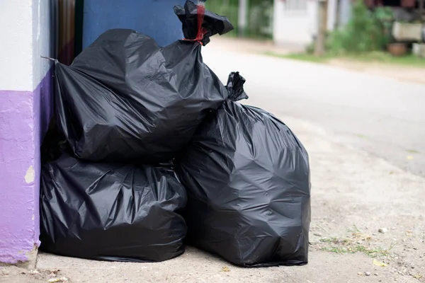 Pile of black plastic bags that contains garbage inside on the floor. Waiting for the rubbish keeper officers to take them away. Concept : Waste management. Collected for disposal.