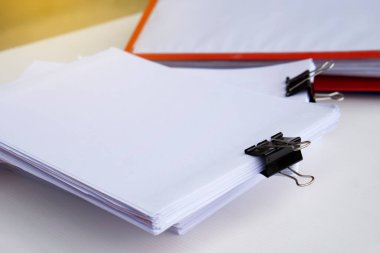 Masanın üzerinde siyah ataçlarla dolu bitirilmemiş kağıt dökümanlarını kapatın. Konsept: belgelerle çalışmak, yıllık rapor hazırlamak, kağıt testi hazırlamak. Eğitim ve iş.