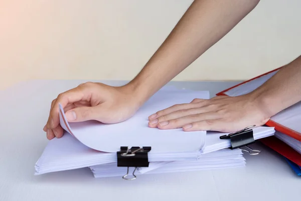 Closeup  hands  opens and checks unfinished paper documents stacked with black paper clips  on desk . Concept : work with documents, doing annual report, prepare paper test. Education and business.