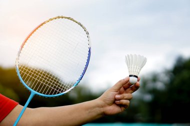 Dışarıda badminton oynamak için el penisi tutuyor. Konsept: ekipmanlı spor, spor. Egzersiz ve takım ya da bireysel rekabet için oynanan eğlence sporu.      