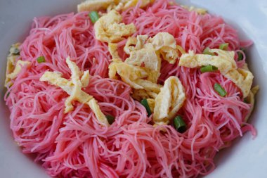 Closeup stir fried pink noodle ,topping with sliced omelet and vegetable, isolated on white background. concept : Thai traditional food. Street food in Thailand.              