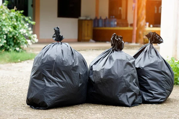 Pile of black plastic bags from house that contains garbage inside . Waiting for the rubbish keeper officers to take them away. Concept : Waste management. Collected for disposal.