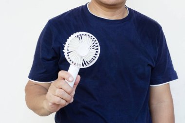 Closeup man hand holds white mini portable electric fan, Concept : Portable electrical equipment that very useful when hot weather.                