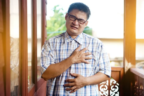 Asian middle aged man feel hurt his chest. pain suffering from heart attack symptom. Concept : health problem that can be happen to anybody.  Emotion and feelings of sickness symptoms. Heart broken.