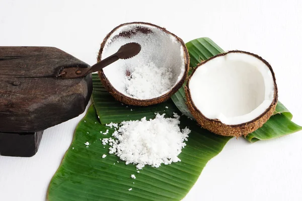 Closeup Coconut grater tool, coconut shell on green banana leaves, prepare coconut milk for food or dessert. Concept Thai traditional cooking method. 