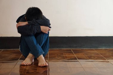 Bunalımlı çocuk yerde tek başına oturur, üzgün hisseder ve ağlar, dizine sarılır. Covid-19 salgınında kendini izole eden ya da evde karantina altına alan bir çocuk. Evimi özledim. Yapayalnız. Korku.   