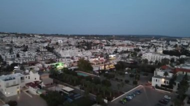 Geceleri dükkanın ışığı ve arabaların hareketi. Kıbrıs, Ayia Napa 'da bir gece. Kamera şehrin üzerinde uçuyor..