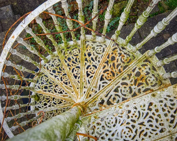 Eski bir binanın balkonuna bağlanmış spiral bir merdiven manzarası. Yüksek kalite fotoğraf. Demir işçiliği eski ve paslı ama metal işçiliğindeki detay ve kalıplar yüksek kalitede..