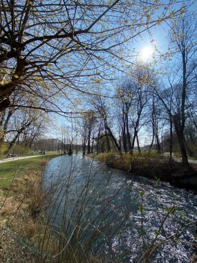 Münih, Almanya 'daki İngiliz bahçesinde güneşli bir günde güzel yansıyan nehir.