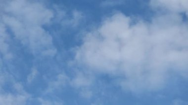 Mavi gökyüzü arka planında beyaz bulutlar hareket ediyor. Zaman aşımı 4K, temiz, kuş yok. Yaz mevsimi konsepti.