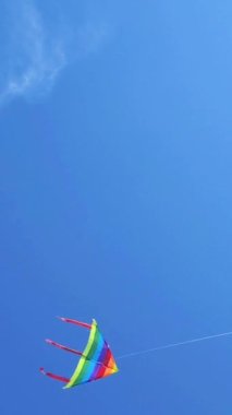 4K Gökkuşağı tarzında uçan bir gökkuşağının görüntüsü. Mavi gökyüzünde yeni çocuklar oynuyor. Aktif açık hava konsept görüntüsü. Yavaş çekim.