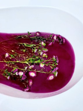 Kırmızı morla banyo. Kasımpatı çiçekli peri suyu. Su yüzeyinde kasımpatı çiçeği, dalgalanmalar ve güneş ışığı yansımalarıyla. Güzellik spa 'sı, rahatlama ya da sağlık tedavisi